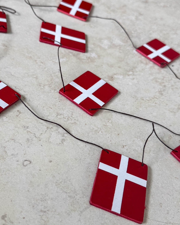 SALUT bunting with Dannebrog flags in red leather on black cord laid on a light stone surface