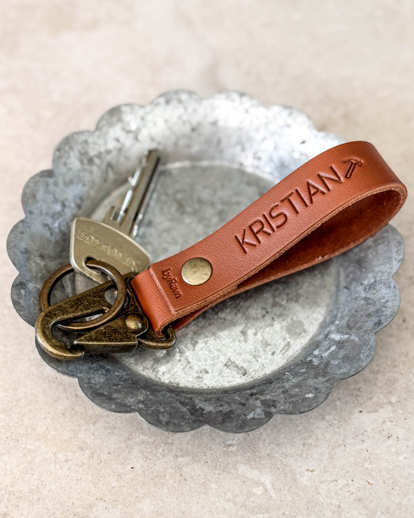 HOOK keyring in cognac leather engraved "KRISTIAN" with an aeroplane symbol, with a key in a metal bowl