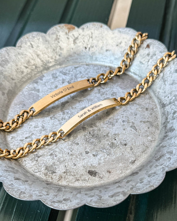 ARA bracelet in gold-plated stainless steel, matte plate with "Victoria ♡ Emil" and polished plate with "Sarah & William", on zinc tray