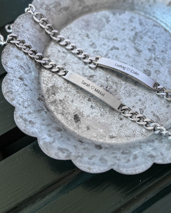 ARA bracelet in silver-coloured stainless steel, matte plate with "Sarah ♡ Mikkel" and polished plate with "Ludvig ♡ Colin", on zinc tray
