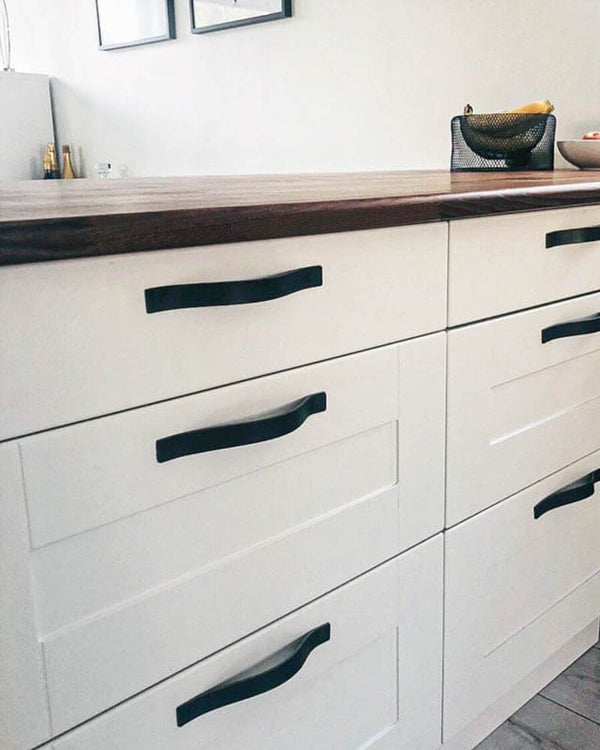 BAND leather drawer pulls in black fitted horizontally on white kitchen drawers under a walnut worktop