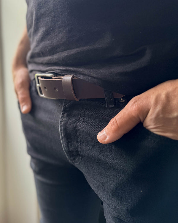 EDGE belt in dark brown leather worn with black jeans and a black t-shirt, hand in pocket