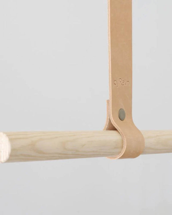 HOLD 15 hanging strap in natural full-grain leather with rivet and byRavn embossing around a light clothes rail