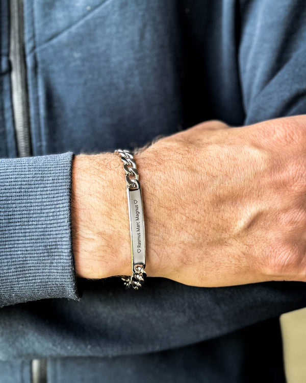 LEO name bracelet in silver-coloured stainless steel with "♡ Rasmus Marc Magnus ♡" engraved, on a man's wrist, blue sweatshirt