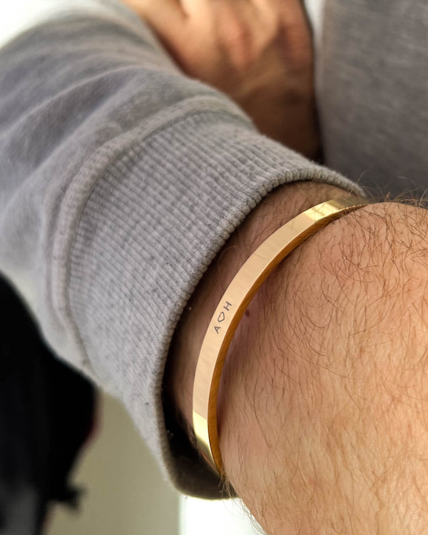 MARS bracelet in gold-plated stainless steel with the initials "A ♡ H" engraved on a man's wrist, grey sweatshirt