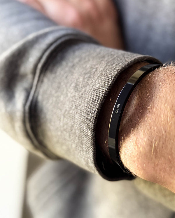 MARS bracelet in black stainless steel with the name "Sarah" engraved, on a man's wrist, grey sweatshirt