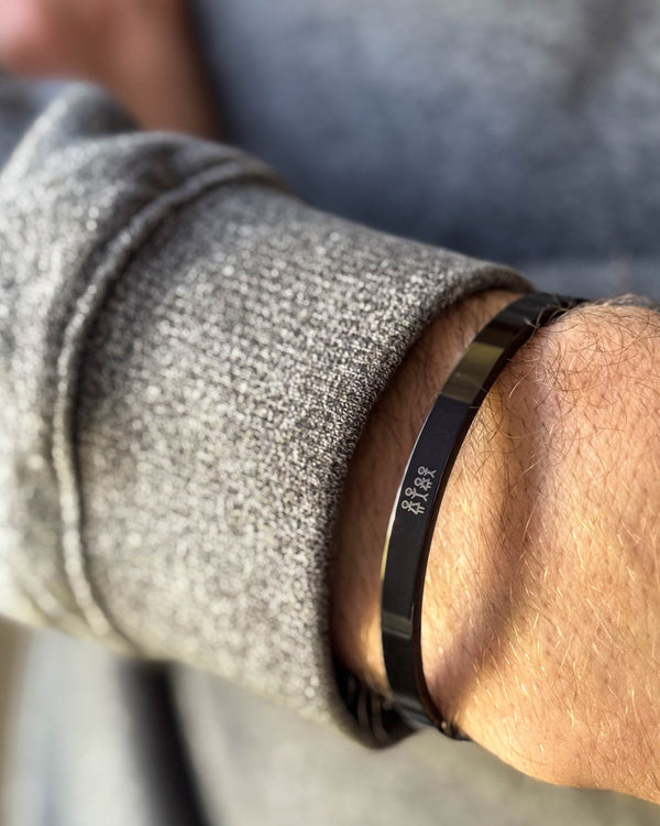 MARS STICK bracelet in black stainless steel with engraved matchstick family, worn on the wrist with a grey knit