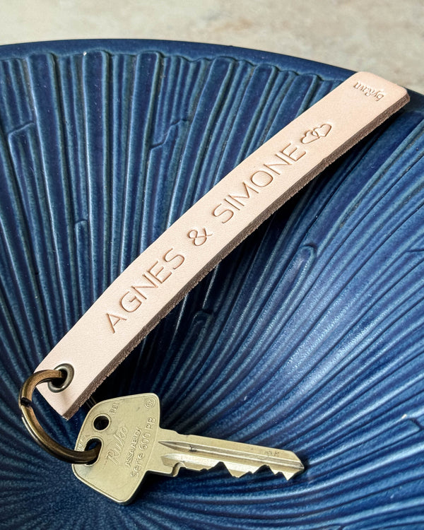 SOLO Large keyring in natural leather with personalised engraving "Agnes & Simone" and hearts, with key in a blue bowl