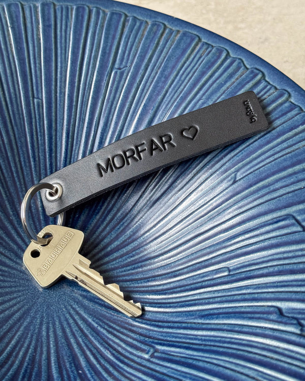 SOLO Medium keyring in black leather with the engraving "Morfar" ♡ and key in a blue ribbed ceramic bowl