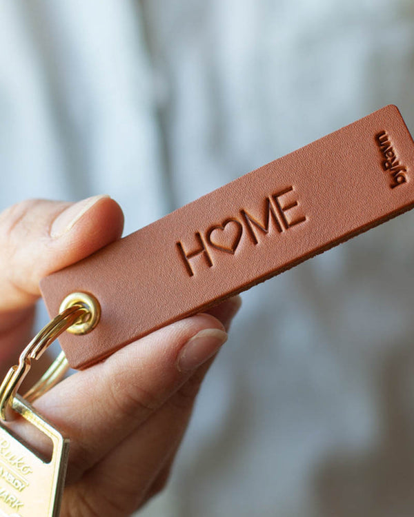 SOLO Small keyring in cognac leather held in hand with key and the engraving "Home", where the O is a heart