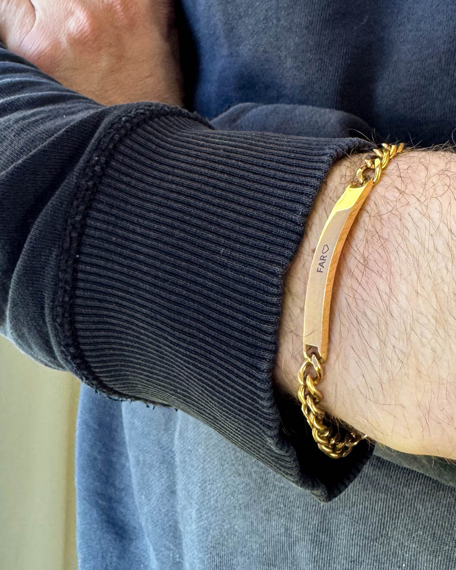 ARA bracelet in gold-plated stainless steel with the engraving "Far" ♡ on a man's wrist, black sweatshirt