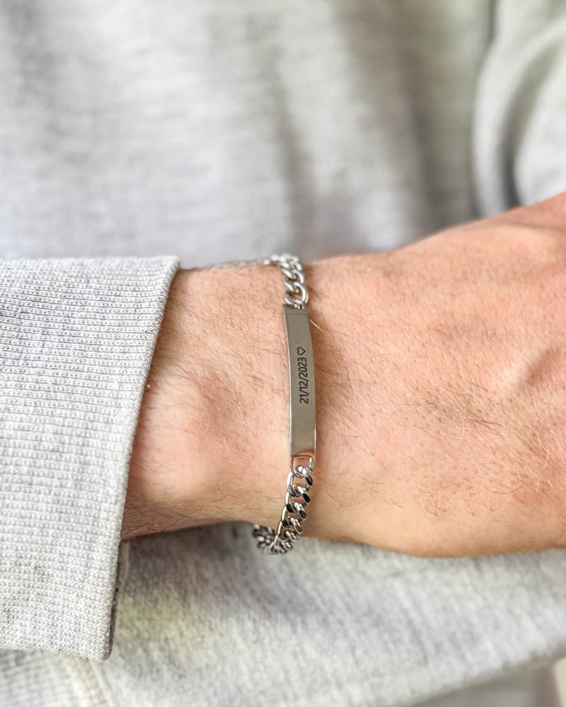 ARA bracelet in silver-coloured stainless steel with the date "21/12/2023" ♡ engraved, worn on the wrist with a light grey sweatshirt
