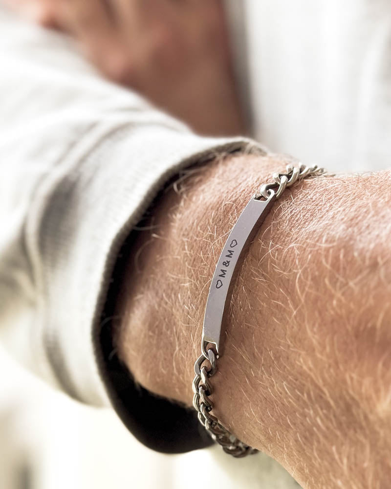 ARA bracelet in silver-coloured stainless steel with the initials "♡ M & M ♡" engraved, on the wrist, white sweatshirt
