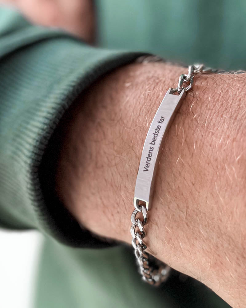 ARA bracelet in silver-coloured stainless steel with the engraving "Verdens bedste far" on a man's wrist, green sweatshirt