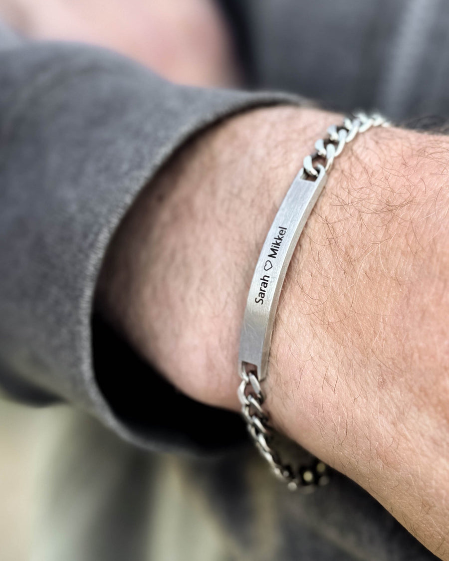 ARA bracelet in brushed silver-coloured stainless steel with "Sarah ♡ Mikkel" engraved, worn on a man's wrist