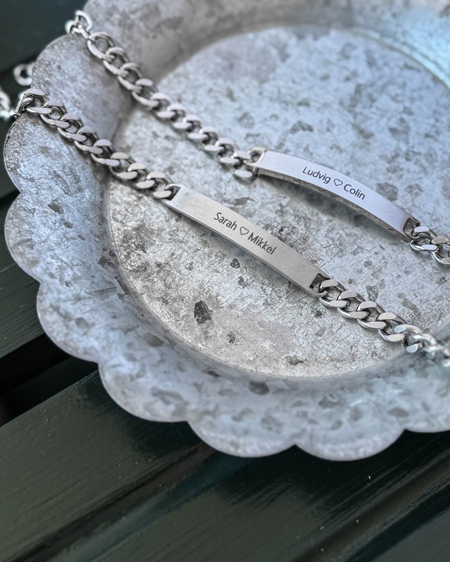 ARA bracelet in silver-coloured stainless steel, matte plate with "Sarah ♡ Mikkel" and polished plate with "Ludvig ♡ Colin", on zinc tray