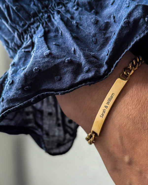 AVA name bracelet in gold-plated stainless steel with the engraving "Sarah & William" on the wrist, navy blue blouse