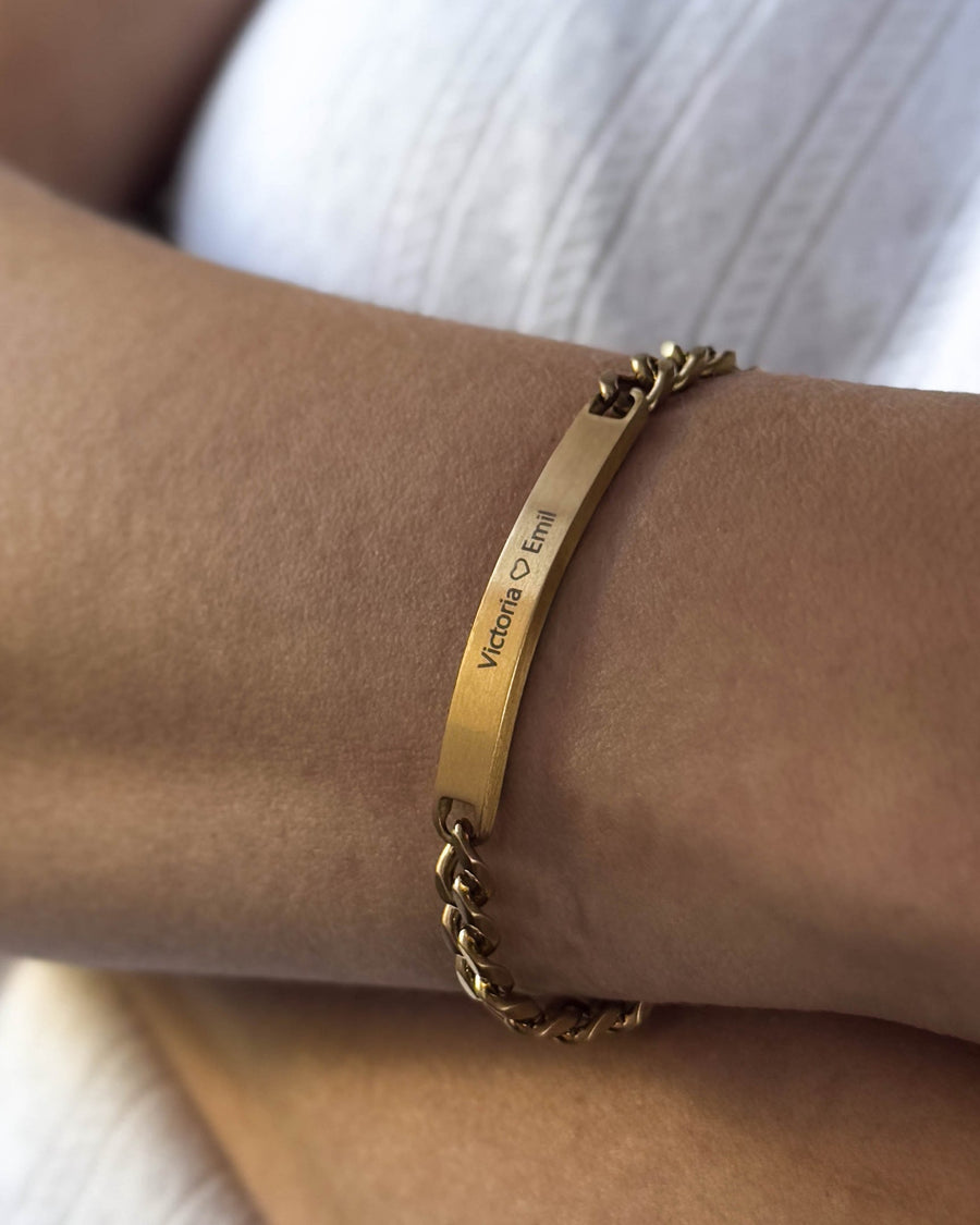 AVA bracelet in brushed gold-plated stainless steel with personalised engraving "Victoria ♡ Emil" worn on the wrist