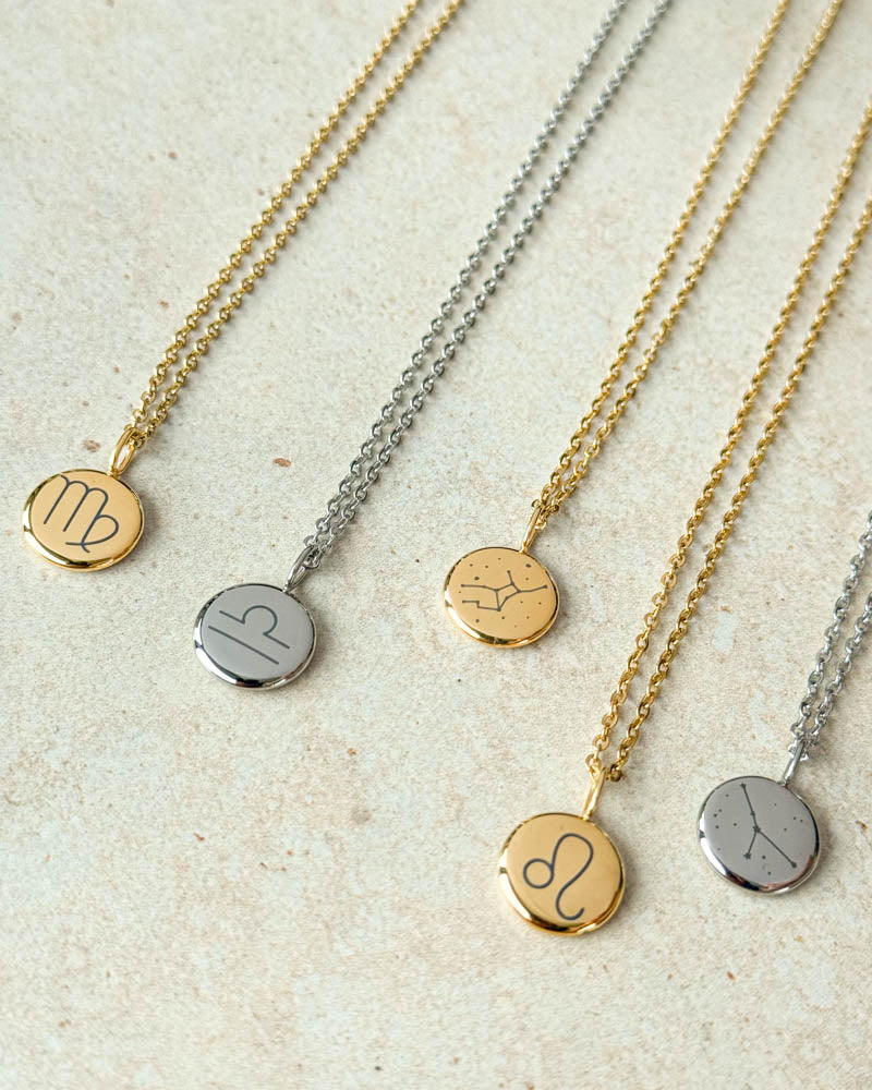 AYA STAR necklaces in gold-plated and silver-coloured steel with Virgo, Libra and Leo zodiac signs and two constellations, on light stone