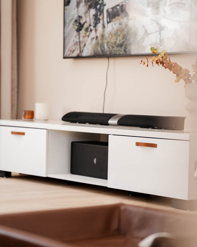 BAND leather drawer pulls in cognac on a white TV unit with two drawers, soundbar and wall-mounted TV in the living room