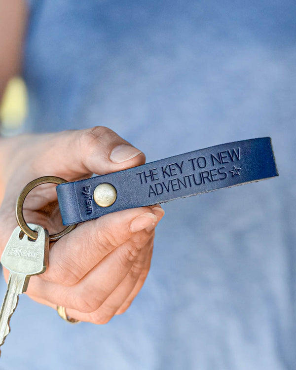 BOND leather keyring in navy blue with personalised engraving "The key to new adventures" ☆, held in hand with key