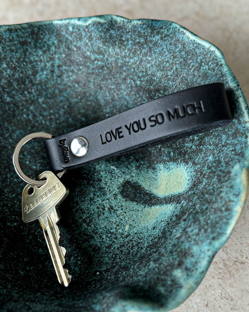 BOND leather keyring in black with personalised engraving "Love you so much" and key in a turquoise ceramic bowl