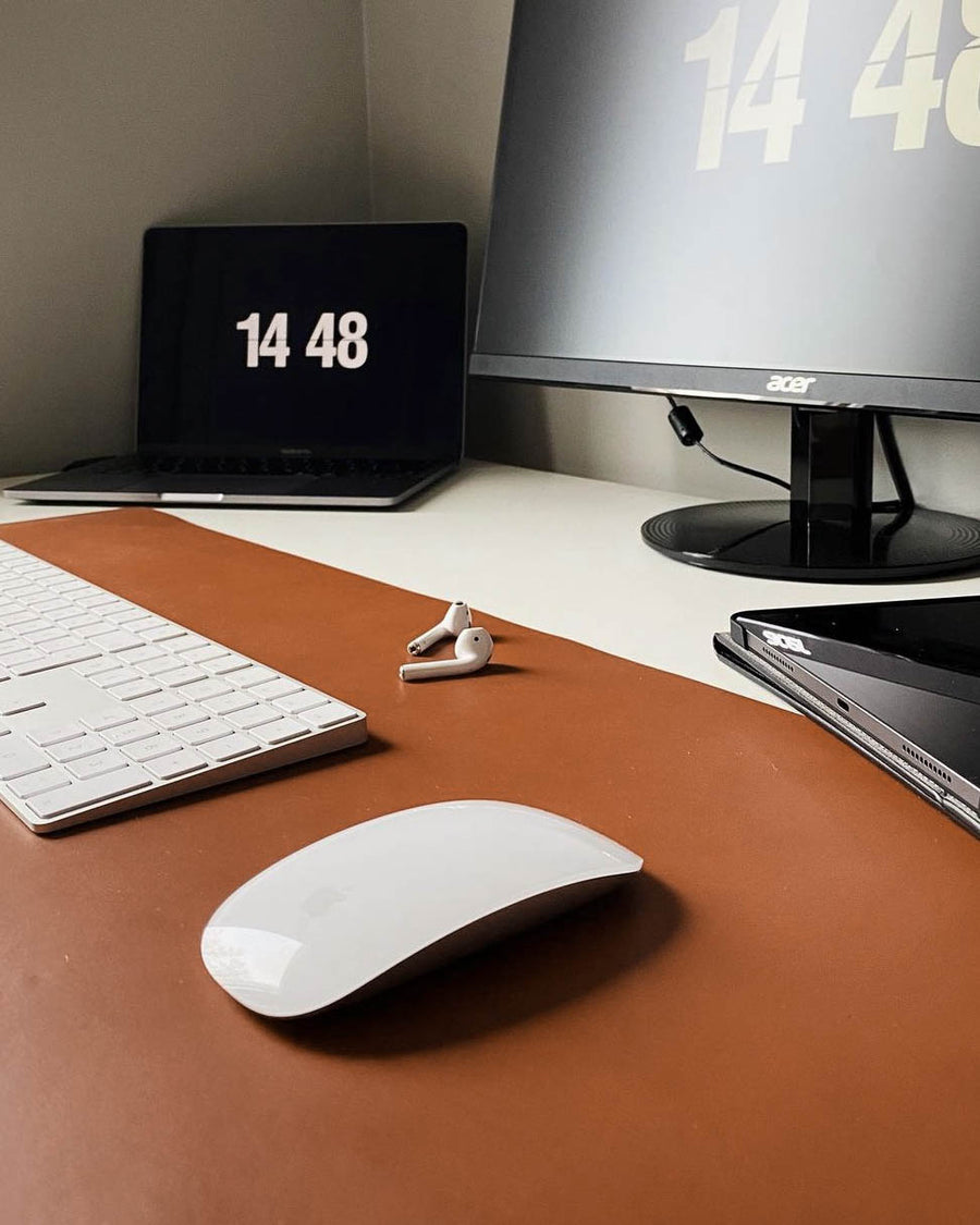 XXL DESK desk pad in cognac leather on a desk with keyboard, mouse, earbuds, laptop and monitor