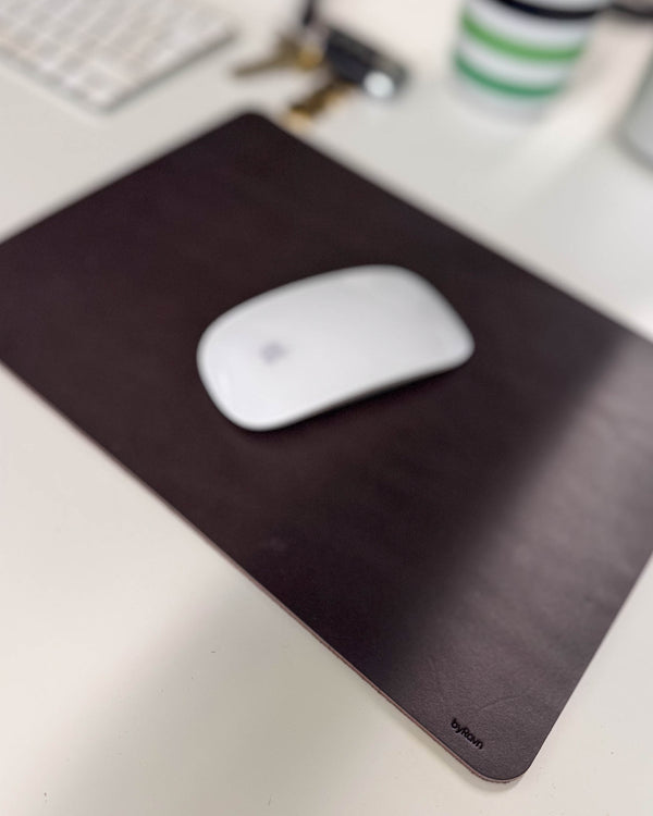 DOS mouse pad in dark brown leather with a white mouse on a desk with keyboard and keys