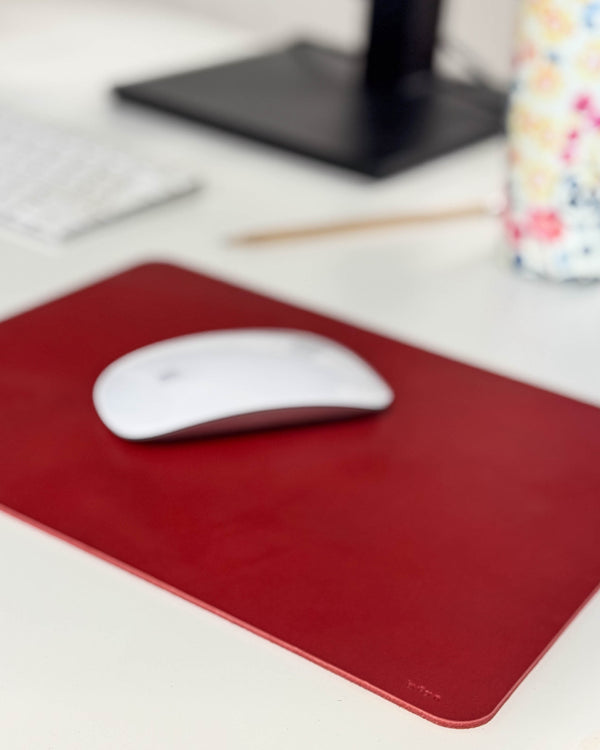 DOS mouse pad in red leather with a white mouse on a desk with keyboard, pencil and floral cup