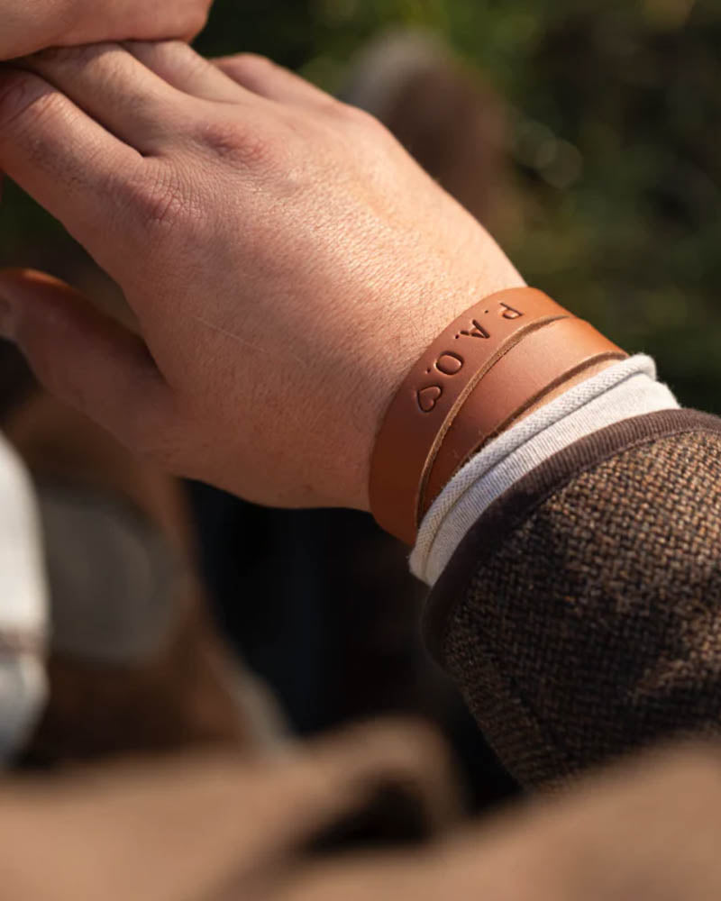 DUO leather bracelet in cognac with the initials "P.A.O." ♡ engraved, worn on the wrist outdoors in sunshine