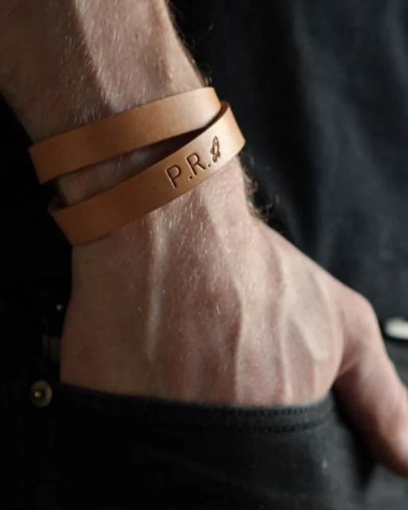 DUO leather bracelet, shown here in light cognac leather, with the initials "P.R." and a small motif engraved on a man's wrist
