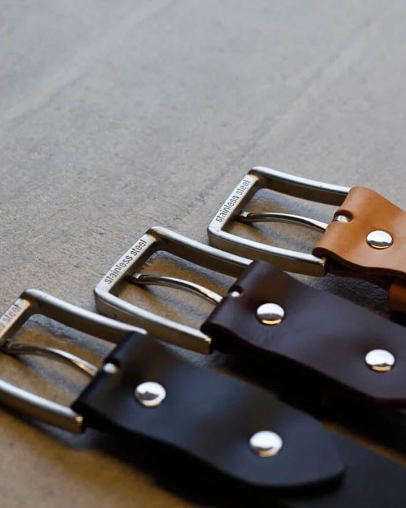 EDGE belts in black, dark brown and cognac leather side by side with stainless steel buckles and rivets