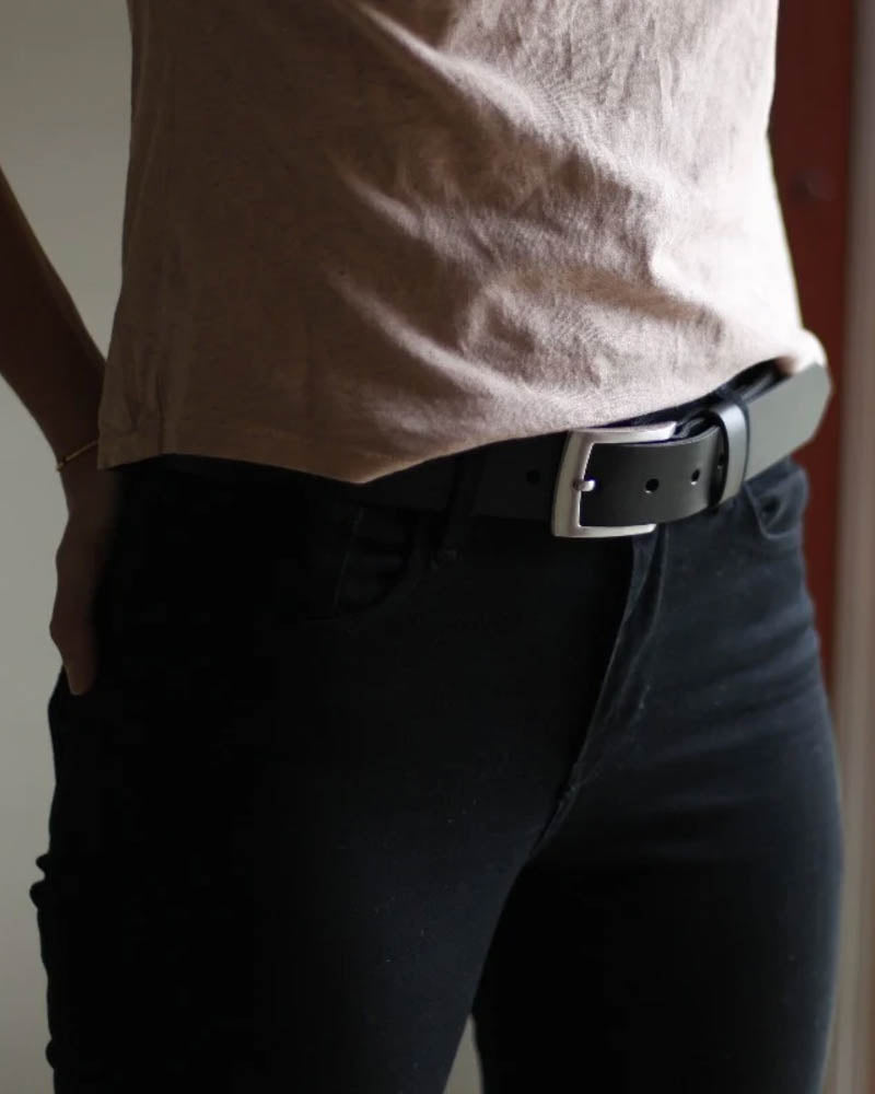 EDGE belt in black leather worn by a woman in black trousers and beige t-shirt, side view