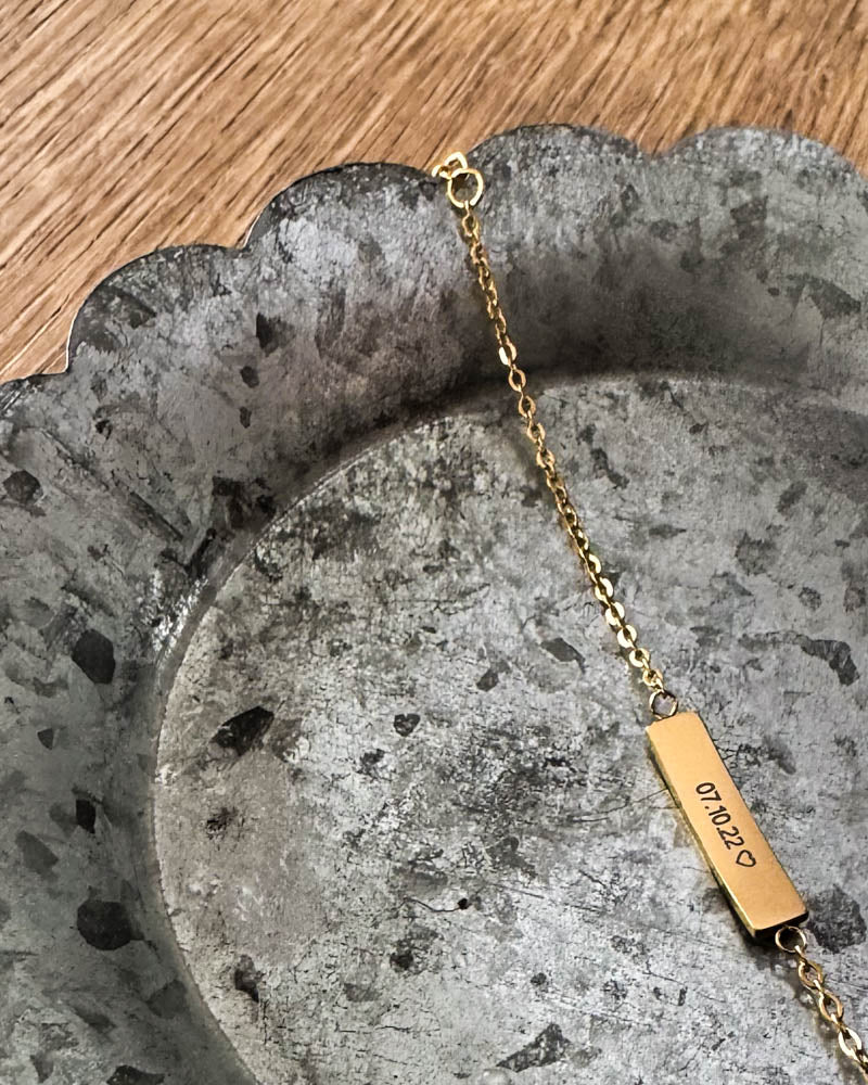 EVI bracelet in gold-plated stainless steel with the date "07.10.22" ♡ engraved on a bar plate, lying on a zinc tray
