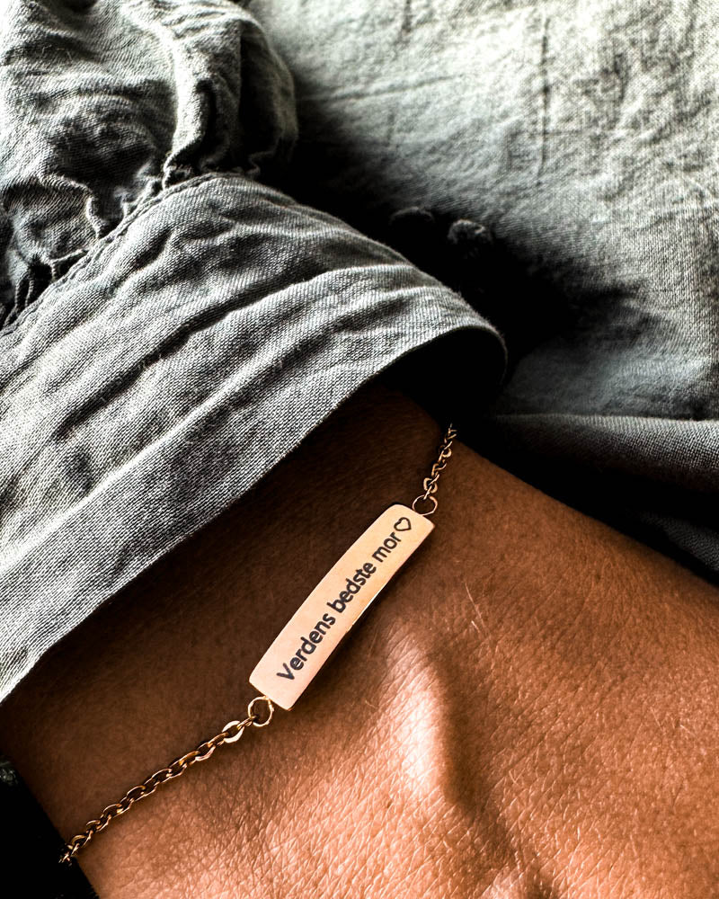 EVI bracelet in gold-plated stainless steel with the engraving "Verdens bedste mor" ♡ on the wrist, grey linen shirt