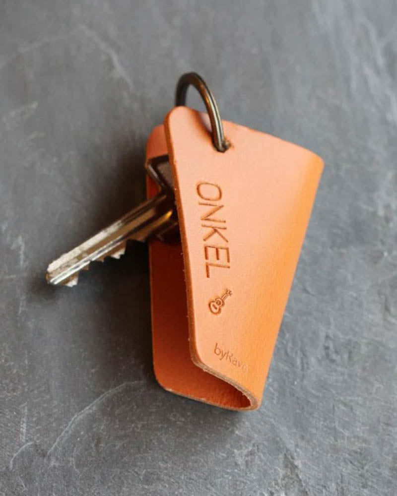 FOLD leather key holder in cognac with the engraving "Onkel" and a small guitar, with keys on dark slate