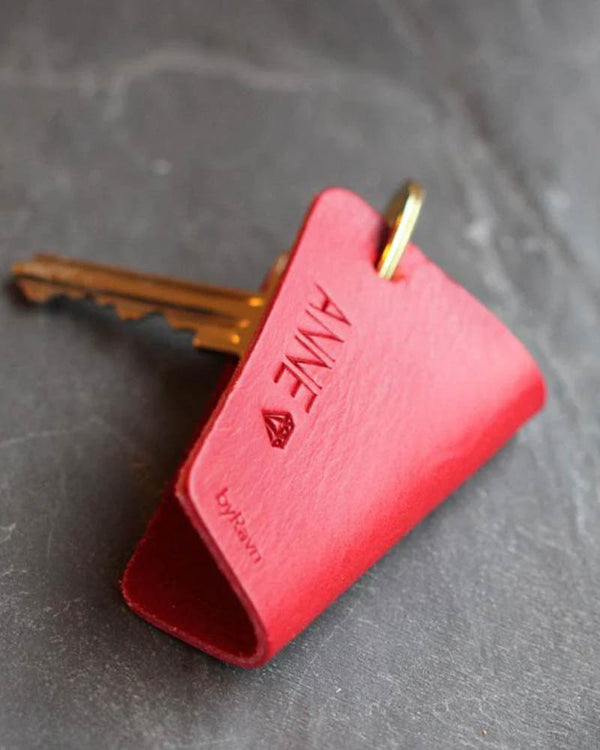 FOLD leather key holder in red with the name "Anne" and a small diamond engraved, with key on dark slate