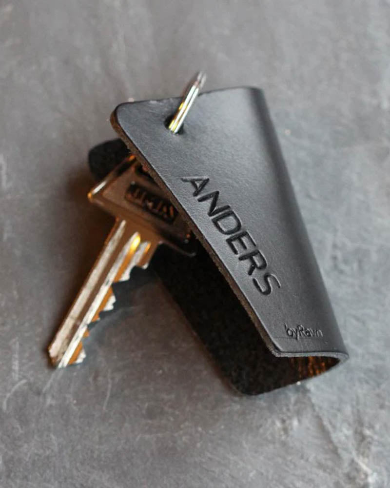 FOLD leather key holder in black with the name "Anders" engraved, with keys on dark slate