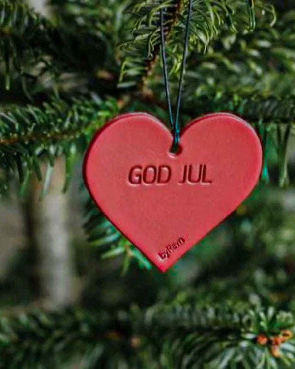 FROST Christmas heart in red leather with the engraving "God jul" hanging in a green Christmas tree