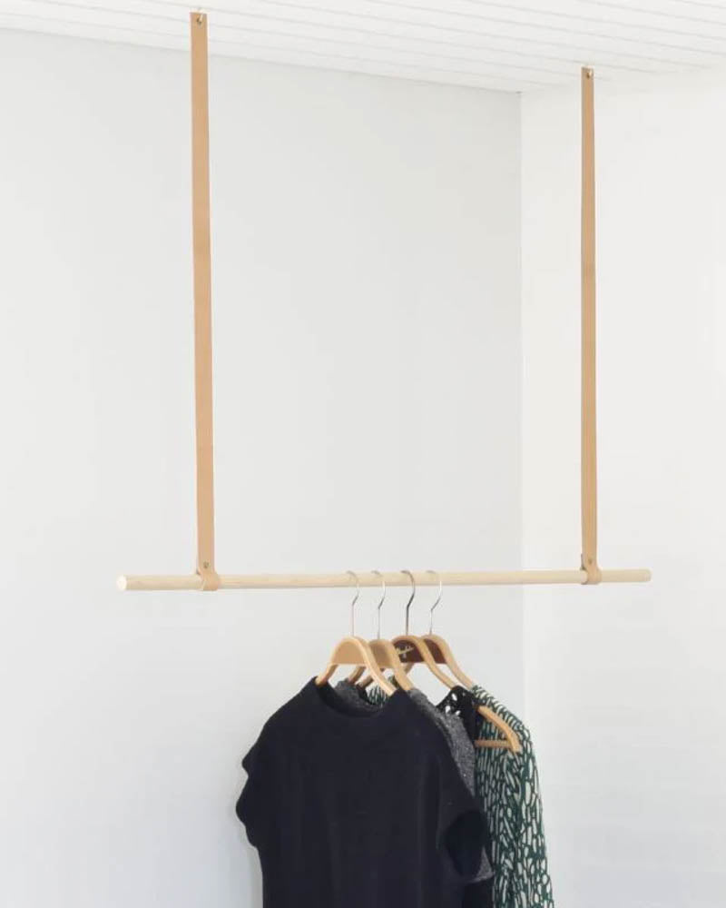 HOLD 15 leather hanging straps in natural hold a clothes rail with clothes on wooden hangers from the ceiling