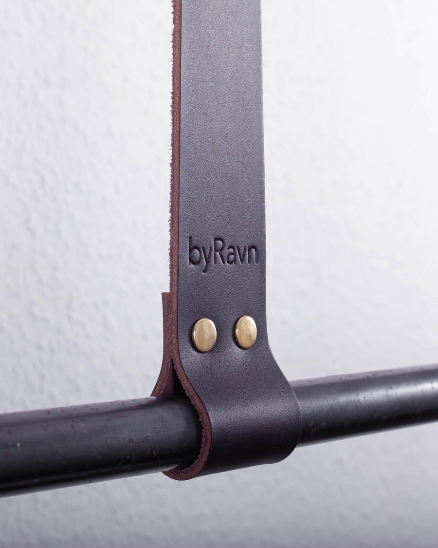HOLD 30 hanging strap in dark brown full-grain leather with two brass rivets and byRavn embossing around a black metal rail