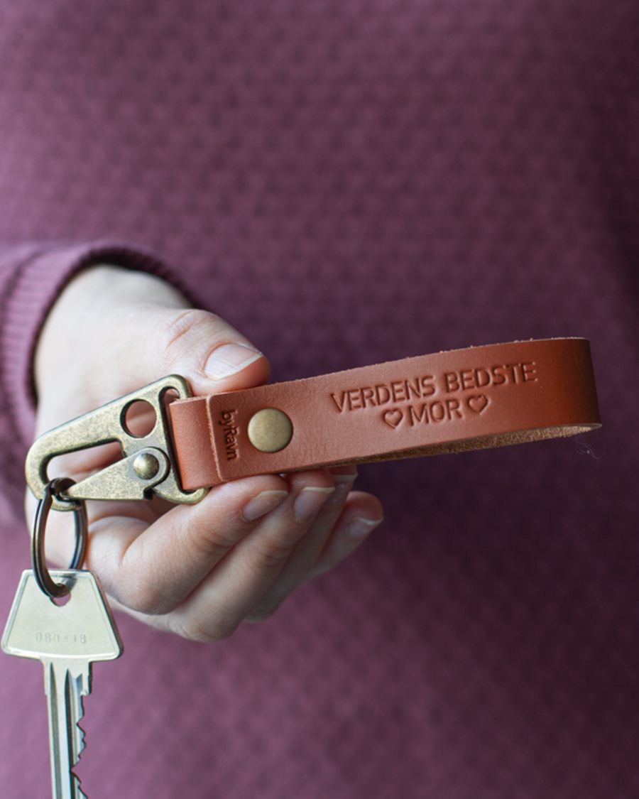 HOOK leather keyring in cognac with the engraving "Verdens bedste mor" and hearts, held in hand with key