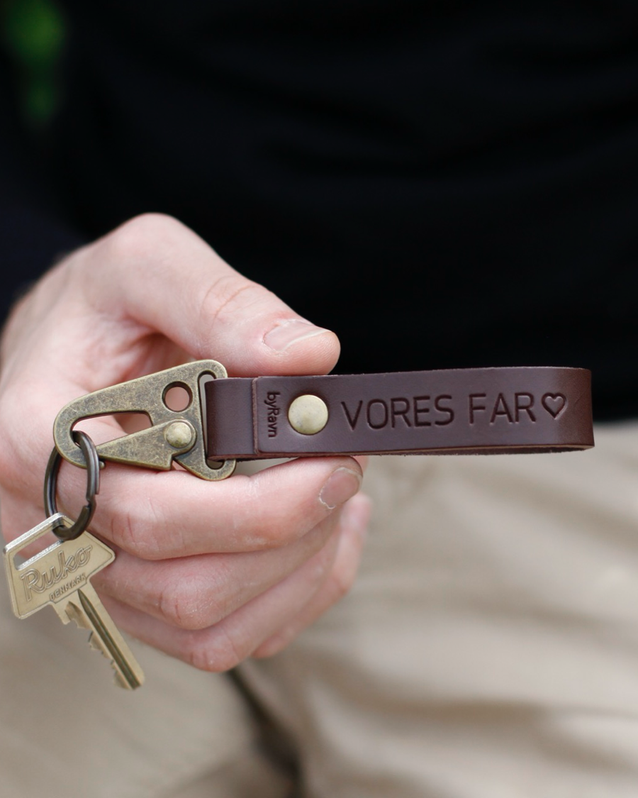 HOOK leather keyring in dark brown with the engraving "Vores far" ♡ and antique brass carabiner, held in hand with key