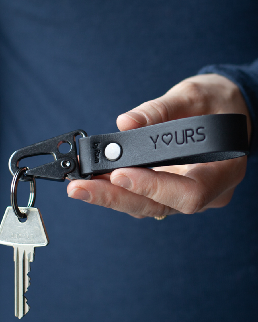 HOOK leather keyring in black with the engraving "Y♡urs" and black steel carabiner, held in hand with key