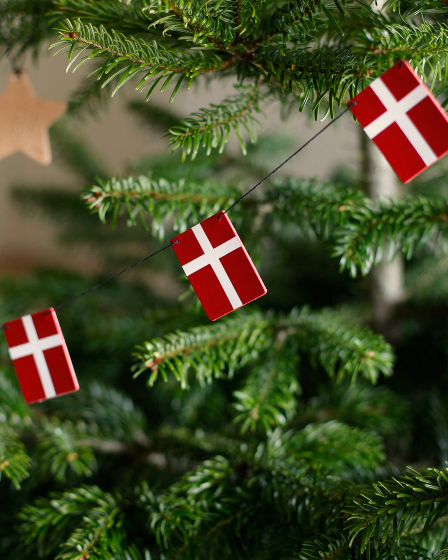 SALUT bunting with leather Dannebrog flags hung as Christmas decoration in a green Christmas tree with wooden star