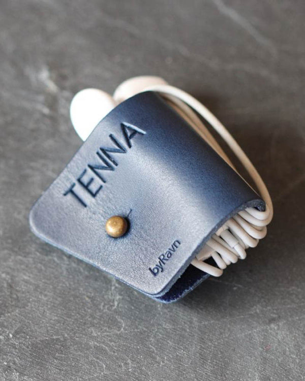 KAX earbud clip in navy blue leather with personalised engraving "Tenna" and cable wrapped around, on dark slate