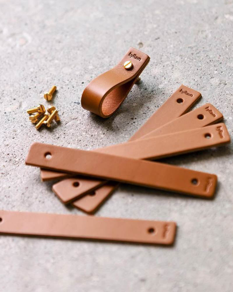 LOOP leather drawer pulls in cognac, several flat leather strips with byRavn embossing, one assembled pull and brass screws