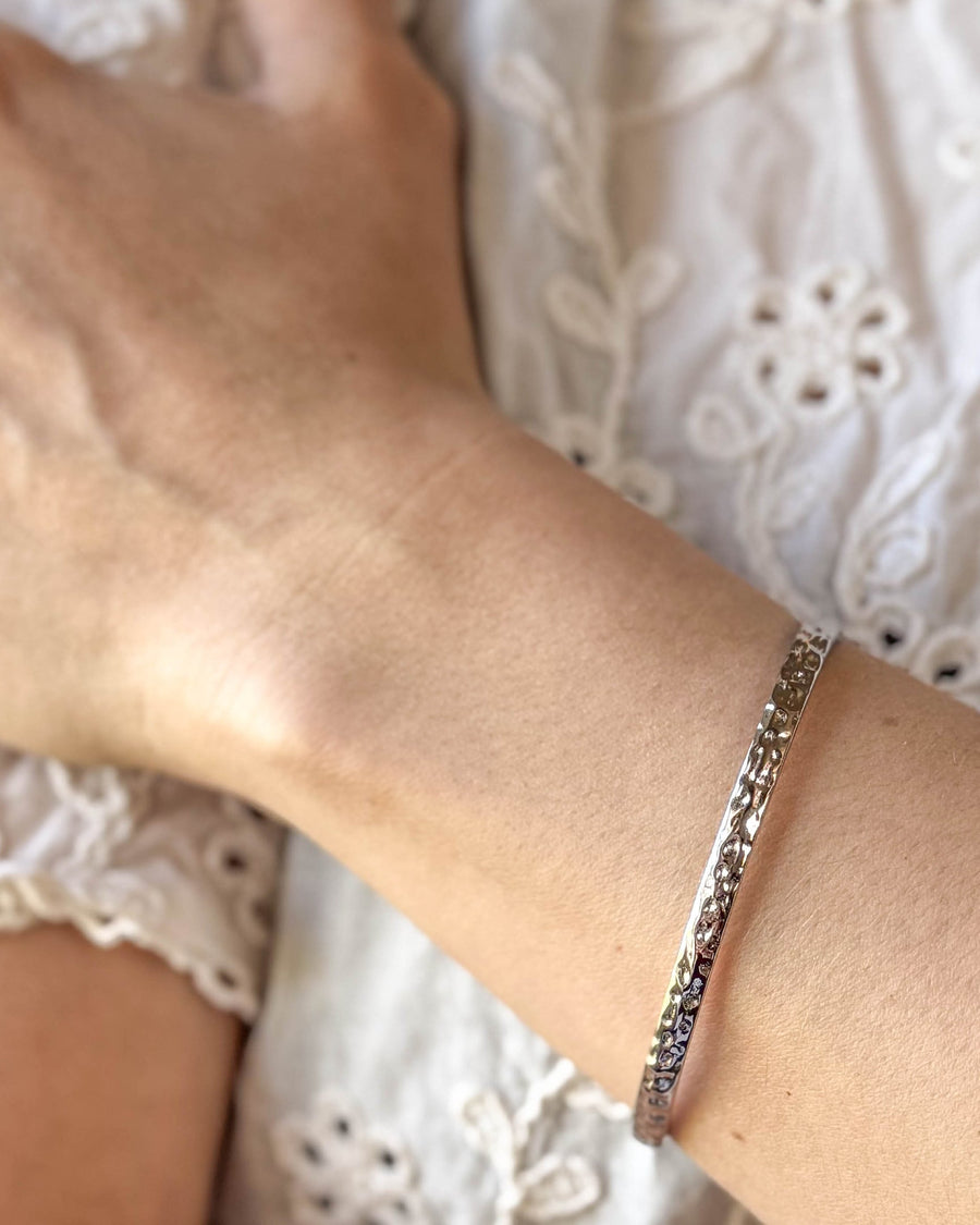 LUNA bracelet in silver-coloured stainless steel, hammered bangle worn on the wrist with a white lace blouse