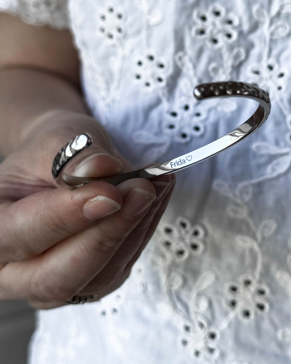 LUNA bracelet in silver-coloured stainless steel held in hand, with the name "Frida" ♡ engraved on the inside