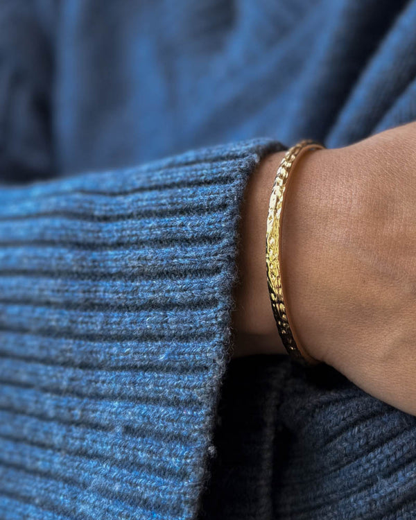 LUNA bracelet in gold-plated stainless steel, hammered bangle worn on the wrist with a blue knit